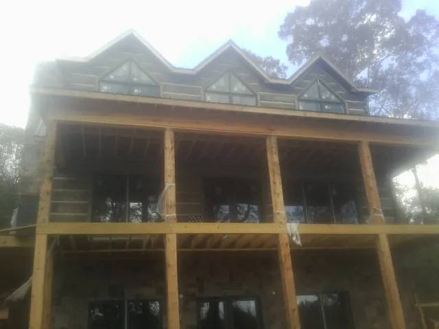 Dormers and porch framing on a large log home under construction — Roof Coating work by our crew in Margaret