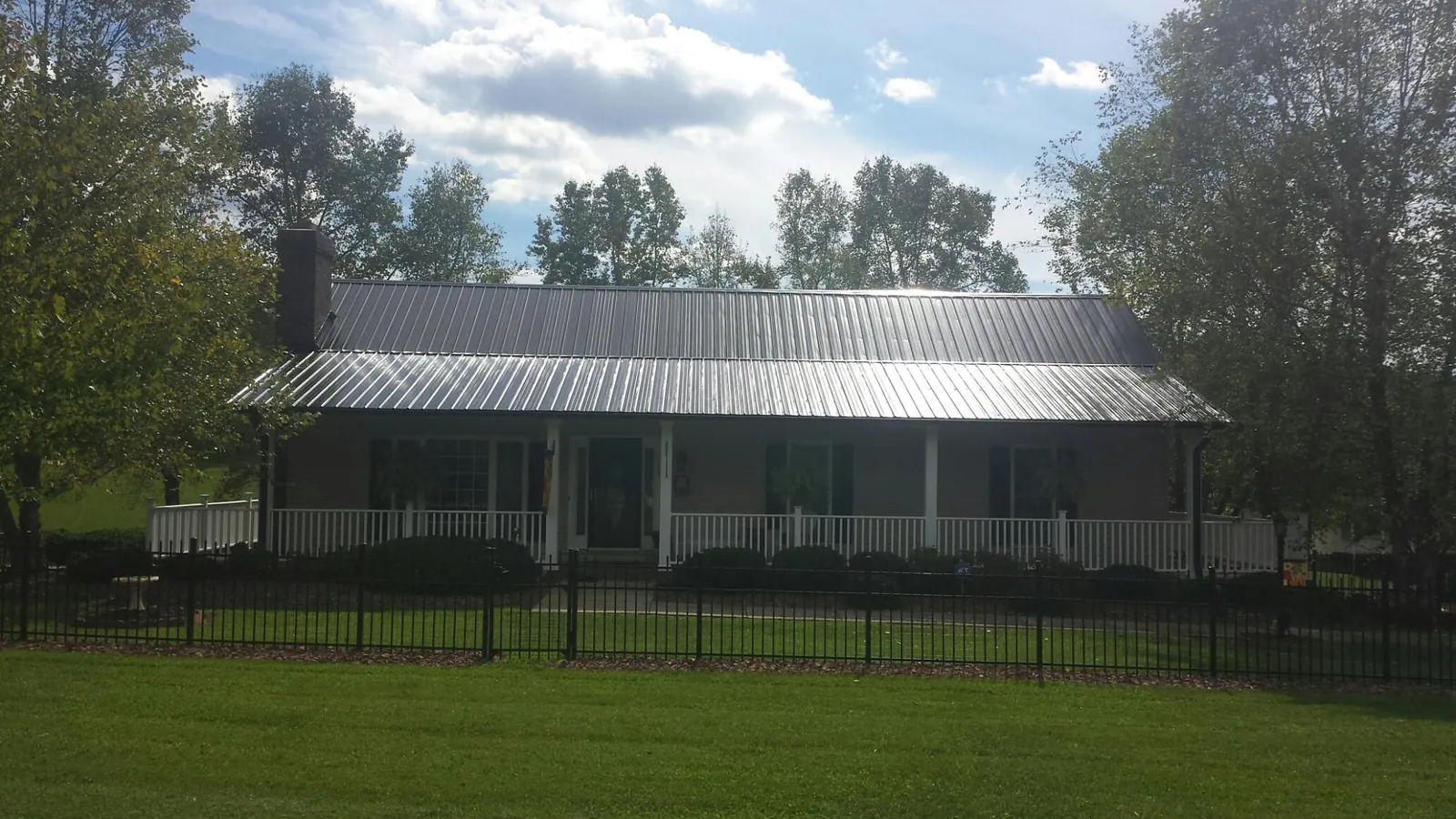 Gray metal roof on a brick ranch with a full width front porch — Gutter Guard Installation work by our crew in Margaret
