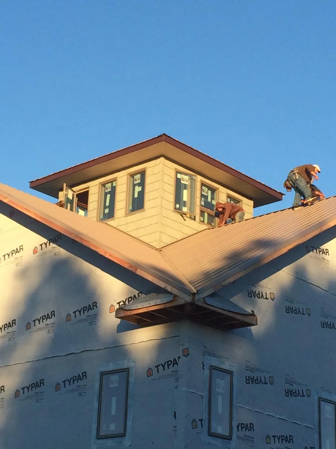 Roofers working around a rooftop cupola on a new metal roof at sunset — Roof Waterproofing in Margaret by Roofing Brothers